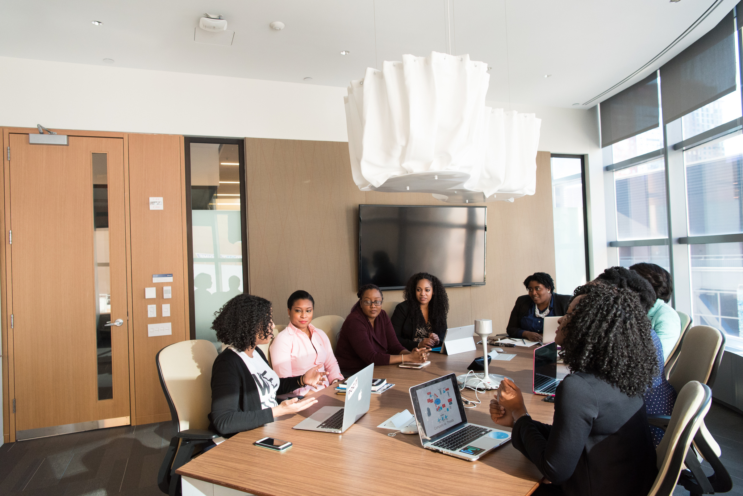 People Sitting Around Brown Wooden Table Under White Pendant Lamp Inside Room